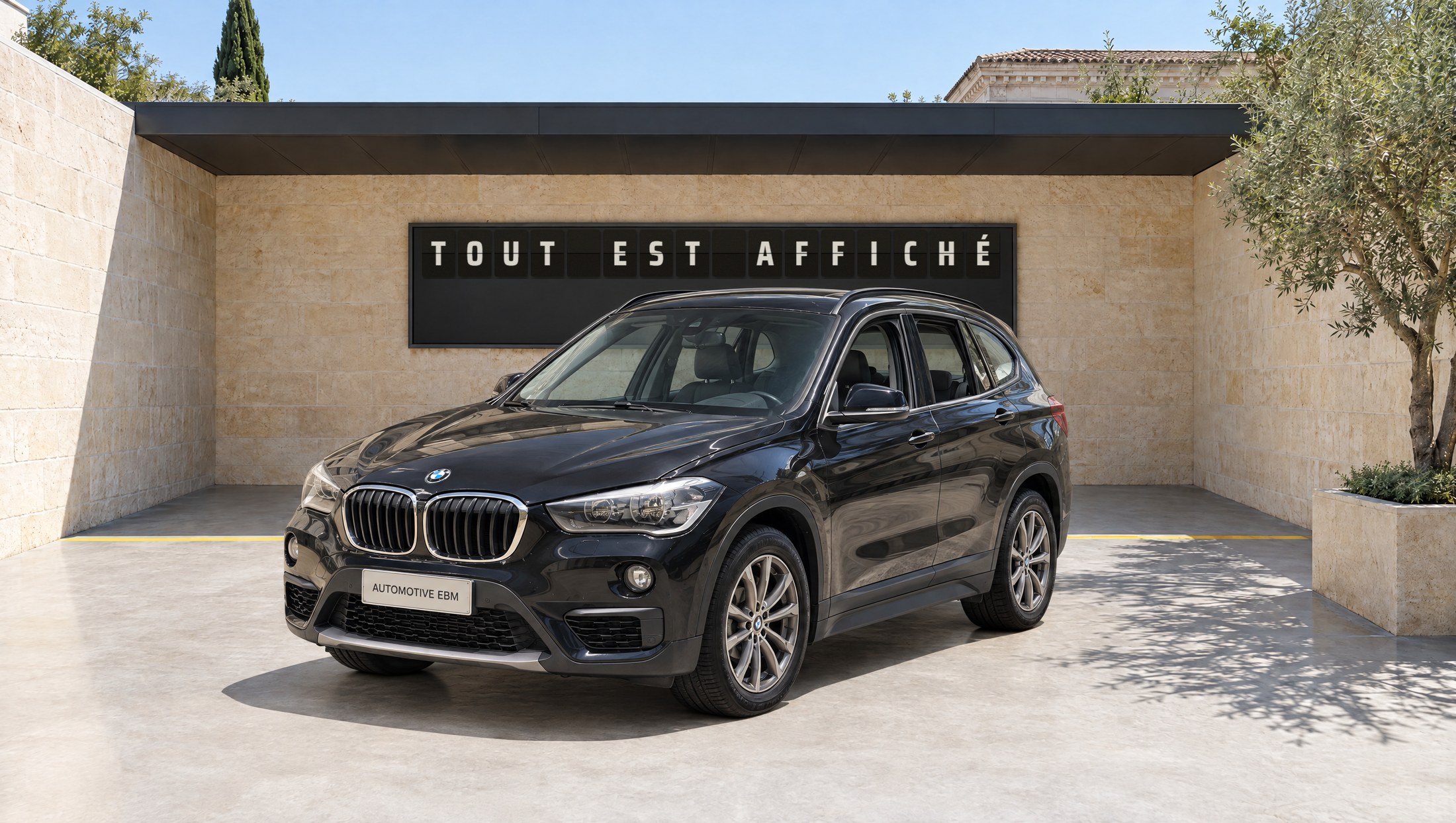 Le BMW X1 dans le décor de pierre de la marque (décor généré) ; au mur, le tableau affiche TOUT EST AFFICHÉ